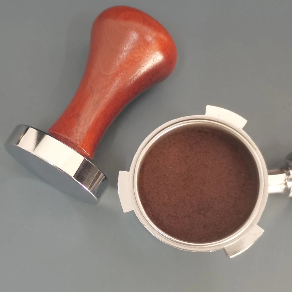 Coffee tamp with red handle and silver base on a gray background