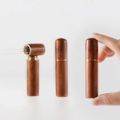 Wooden pepper grinder with a hand holding it on a white background