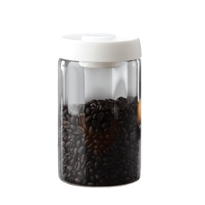 Clear container with white lid filled with coffee beans on a white background