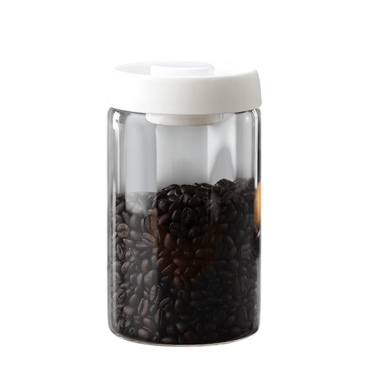 Clear container with white lid filled with coffee beans on a white background