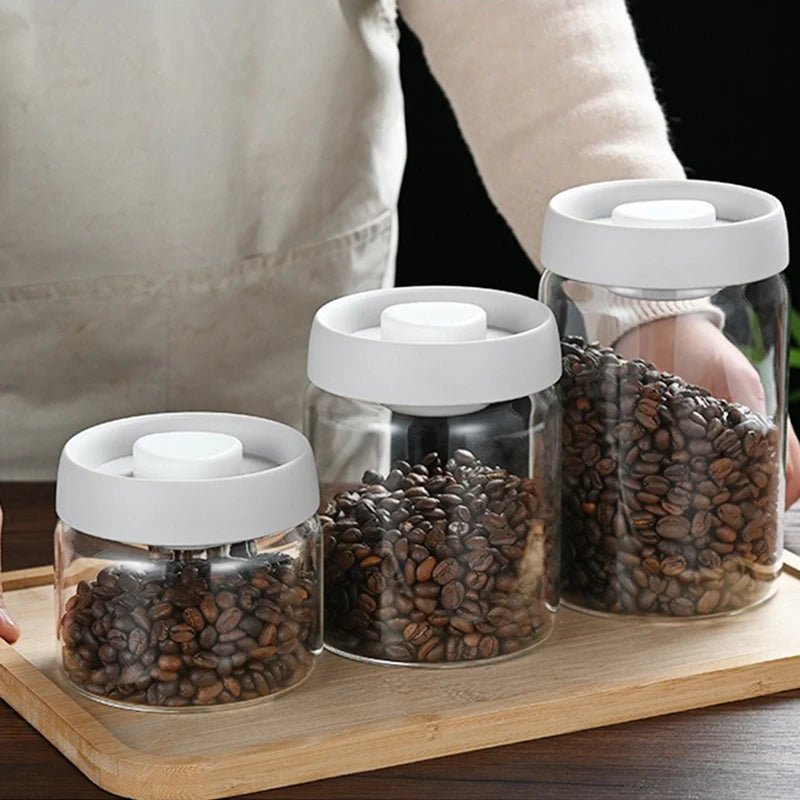 Three glass jars with white lids containing coffee beans on a wooden tray.