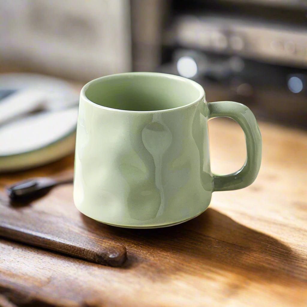 Green ceramic mug on a wooden surface with a blurred background