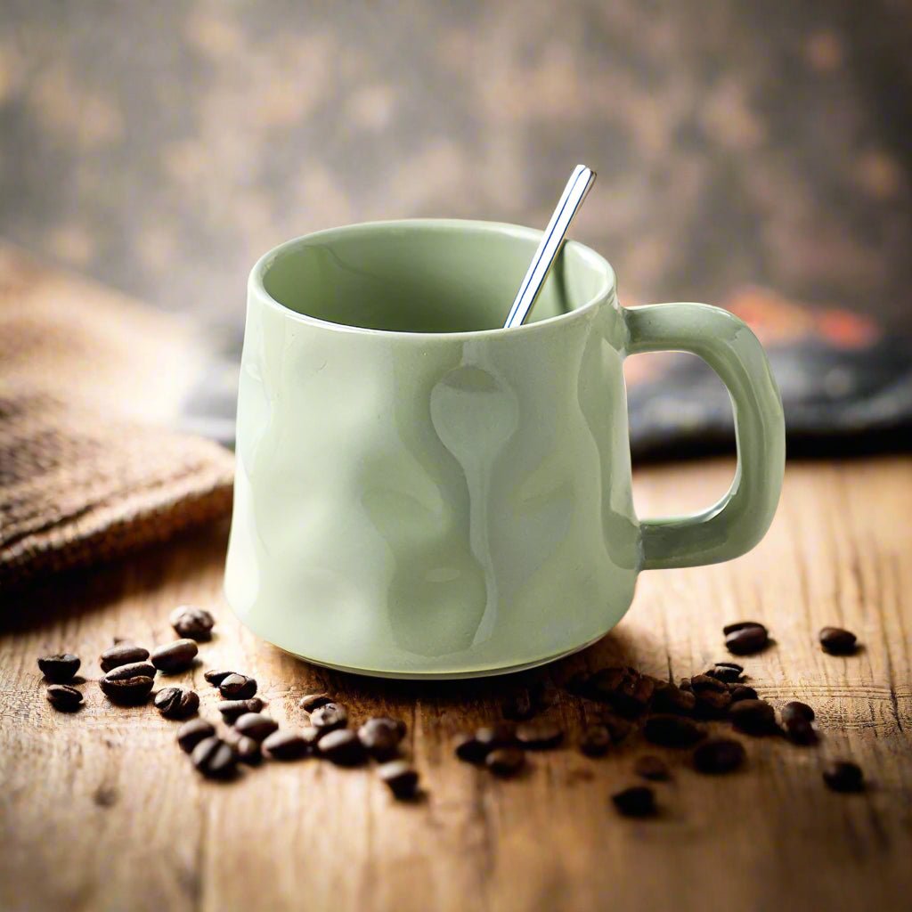 Green mug with a spoon and coffee beans on a wooden surface