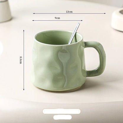 Green ceramic mug with a spoon inside, shown with dimensions on a light background