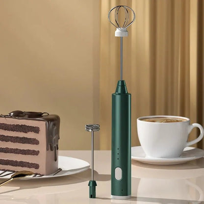 Green handheld milk frother next to a cup of coffee and a slice of cake on a beige background