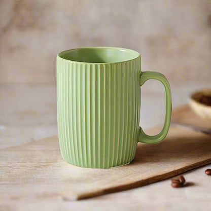 Green ceramic mug with ribbed texture on a wooden surface.