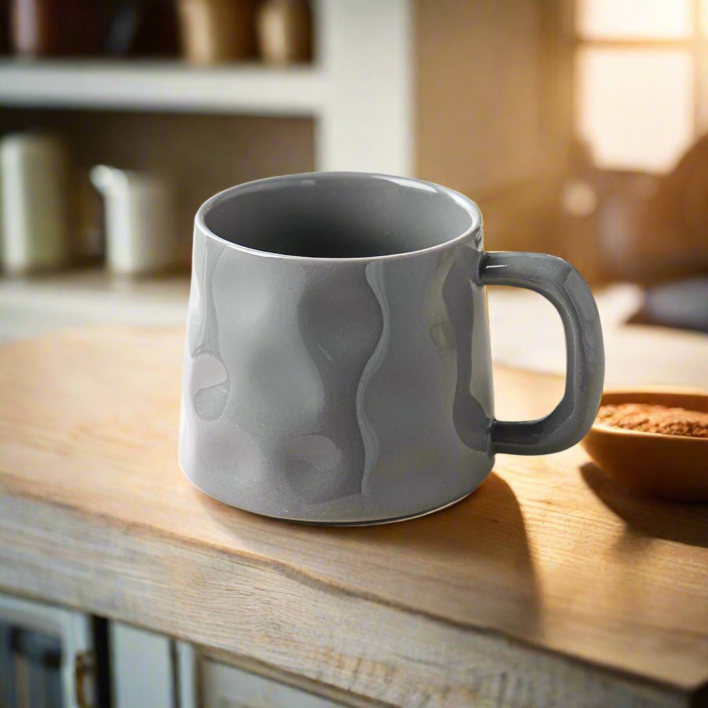 Gray textured mug on a wooden surface with a blurred kitchen background