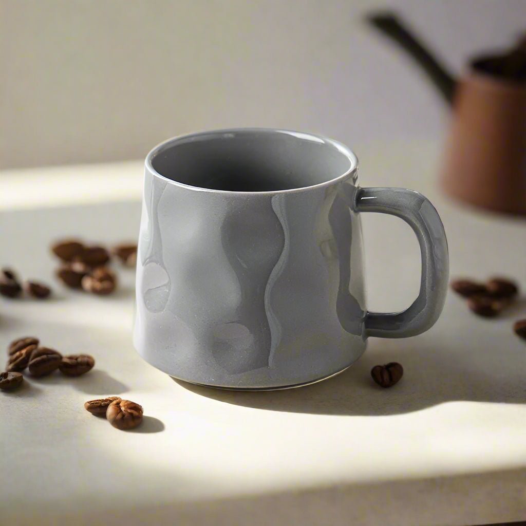 Gray ceramic mug with wavy design on a light surface with coffee beans around