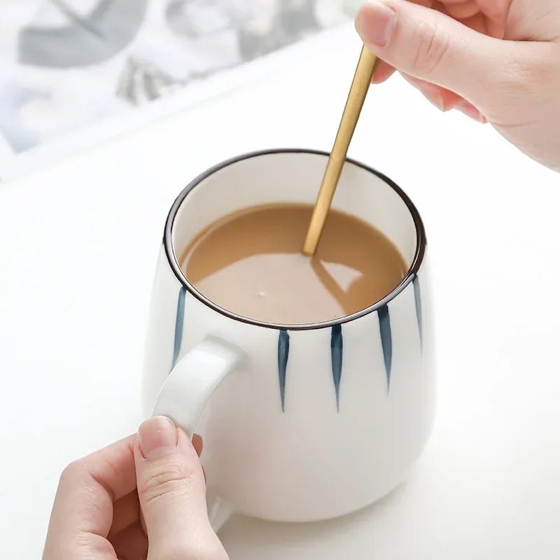 Person stirring a cup of coffee with a spoon on a white background