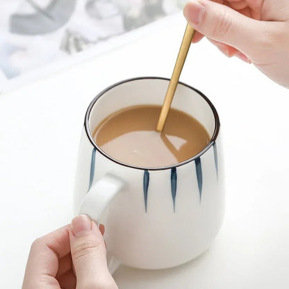 Person stirring a cup of coffee with a spoon on a white background