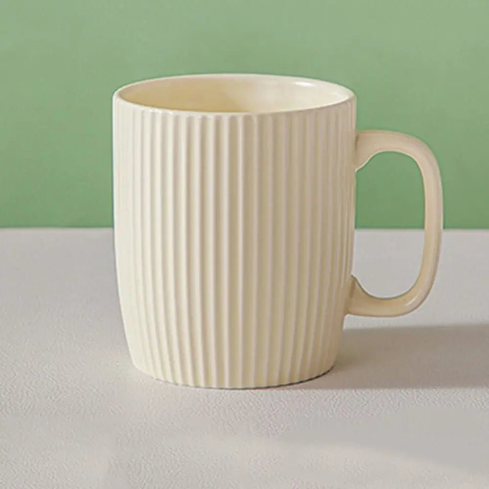 Beige ceramic mug with ribbed texture on a white surface with a green background