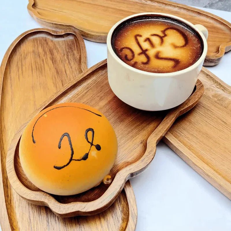 Cup of coffee with latte art and a round pastry on a wooden tray.