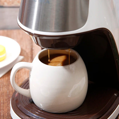 Coffee being poured from a coffee maker into a white mug on a wooden surface.