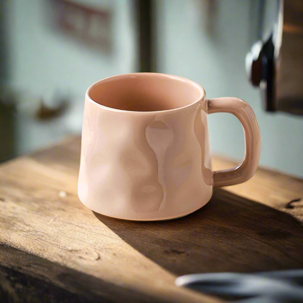 Pink ceramic mug on a wooden surface with a blurred background