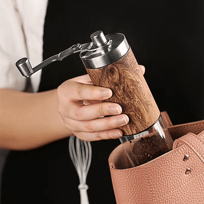 Hand holding a wooden coffee grinder with a black background