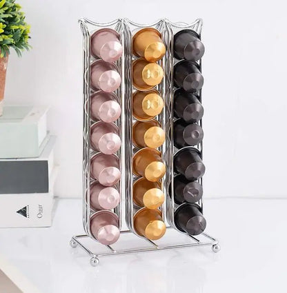 Metallic capsule organizer with pink, gold, and black capsules on a white surface.
