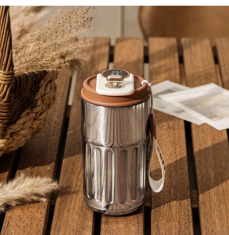 Silver tumbler with a brown lid on a wooden surface