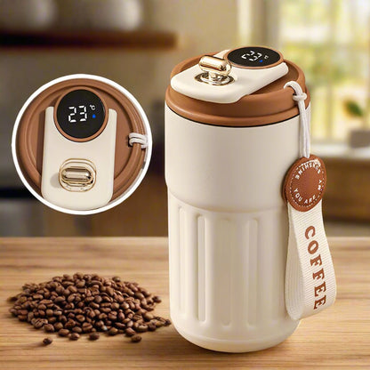 White coffee thermos with brown lid on a wooden surface, surrounded by coffee beans.