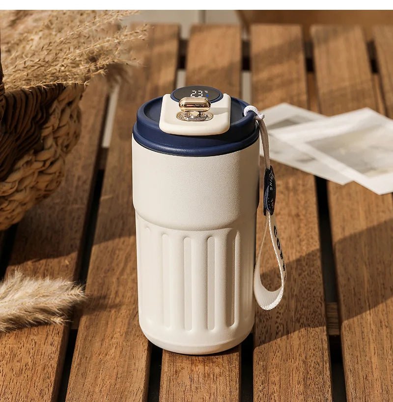 White tumbler with blue lid on a wooden surface