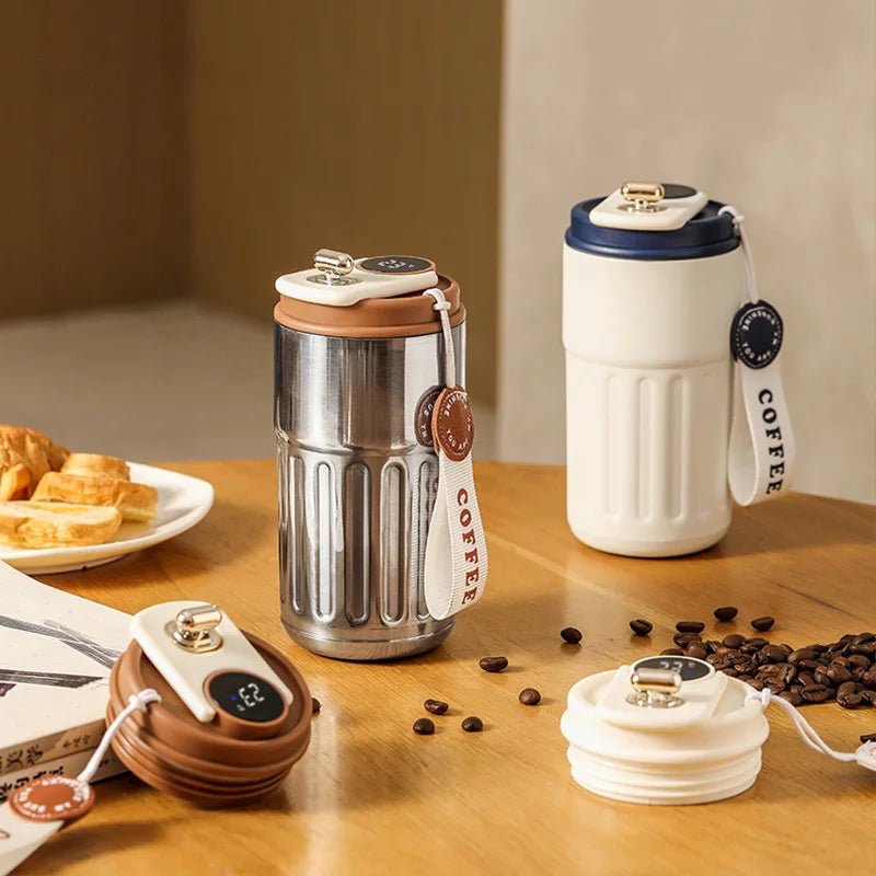 Two coffee-themed tumblers on a wooden table with coffee beans and pastries.