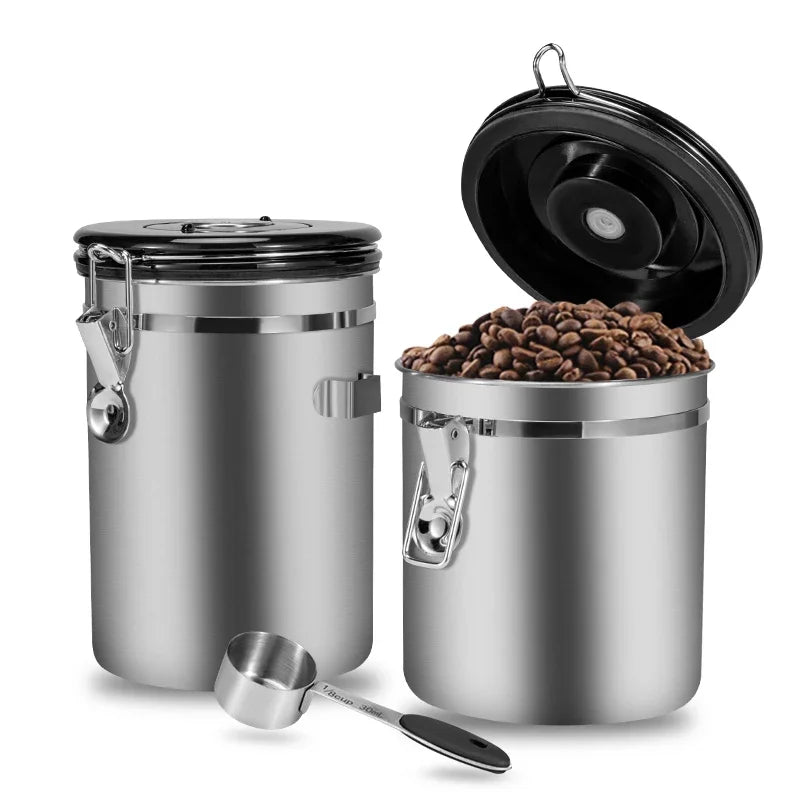 Stainless steel coffee canister with beans and a scoop on a white background