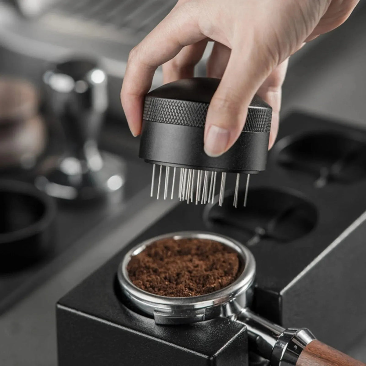 Hand using a coffee grinder to grind coffee beans on a coffee machine.