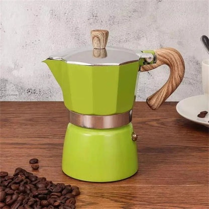 Green espresso maker with wooden handle on a wooden surface with coffee beans.