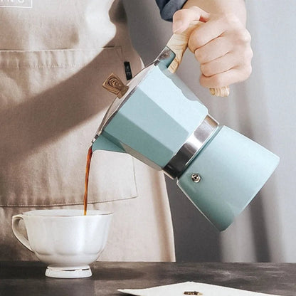 Person pouring coffee from a teal French press into a white mug.
