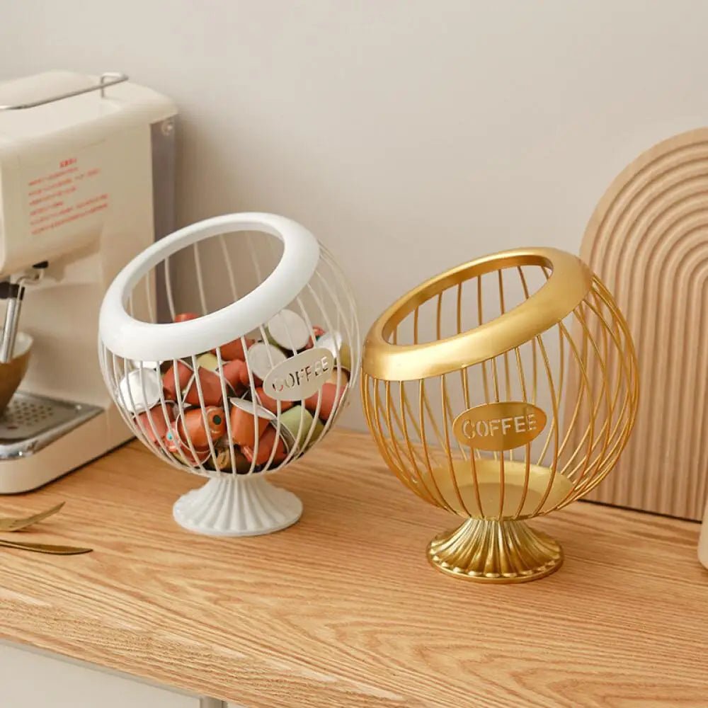 Two decorative wire baskets, one white and one gold, on a wooden surface with a sewing machine in the background.