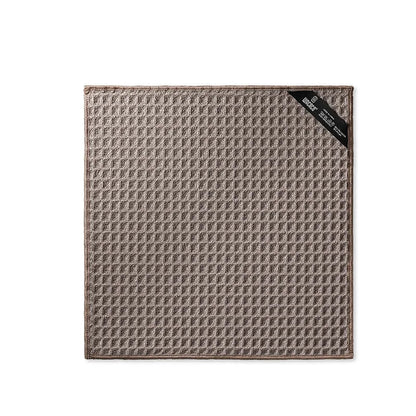 Textured brown towel with a black corner label on a white background