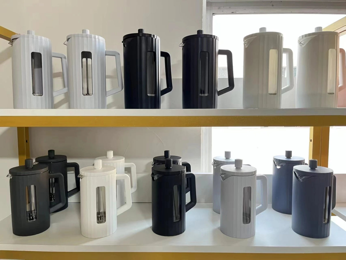 Collection of variously colored French press coffee makers on shelves.