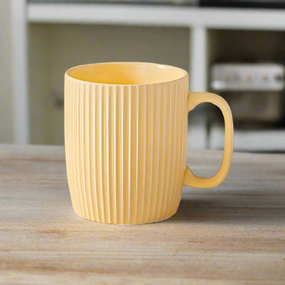 Yellow mug with ribbed texture on a wooden surface